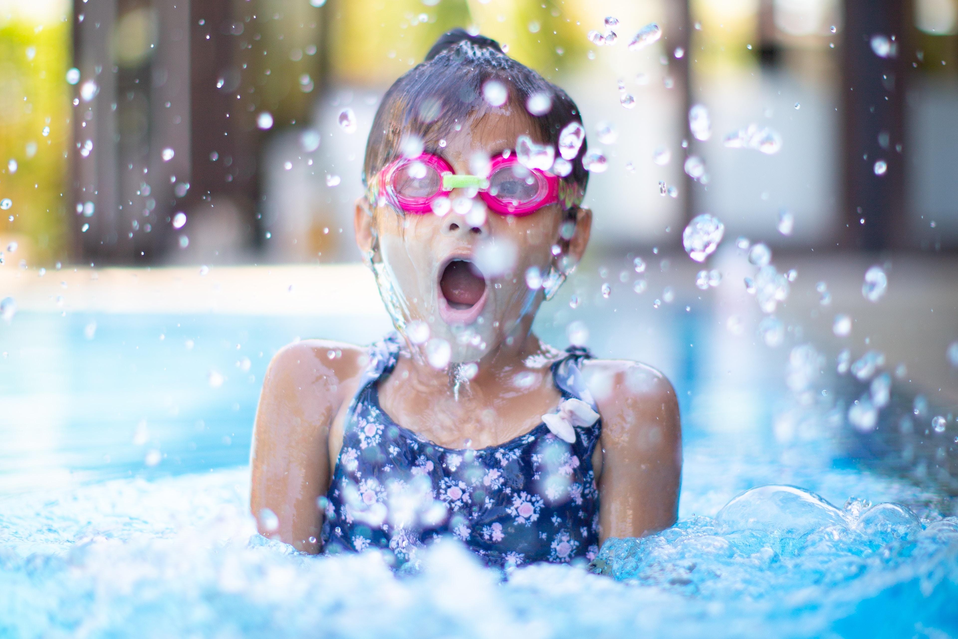 Girl with goggles splashing in a pool